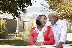 Senior black couple standing outside their new house