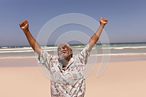 Senior black man with arms outstretched standing on beach