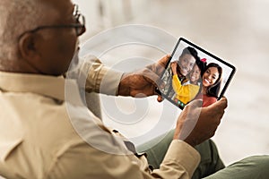 Senior black man calling his family, using digital tablet
