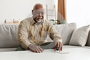 Senior Black Man Measuring Oxygen Saturation Using Pulse Oximeter Indoor