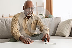 Senior Black Man Measuring Saturation Level Using Pulse Oximeter Indoors