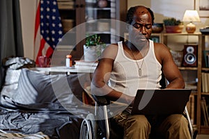 Senior Black Man in Wheelchair Working Remotely on His Portable Computer