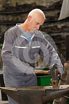 senior blacksmith forge iron at work