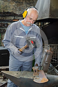 Senior blacksmith forging molten metal on anvil