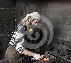 Senior blacksmith forging the molten metal on the anvil in smith