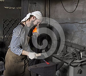 Senior blacksmith forging the molten metal on the anvil in smith