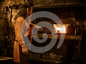 Senior blacksmith heats item before forging in smithy