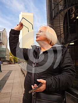 senior blonde business woman looks at her glasses photo