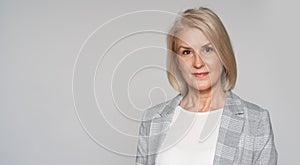 Senior blonde woman is smiling isolated on grey