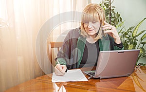 Senior blonde woman writing down an order