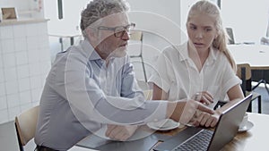 Senior boss in eyeglasses discussing with female assistant