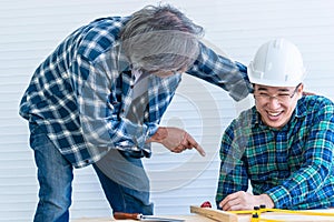 Senior builder bragging and helping a younger worker in home improvement project photo