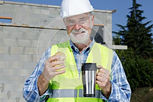 senior builder eats cake and has coffee