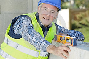 senior builder posing with spirit level at construction site