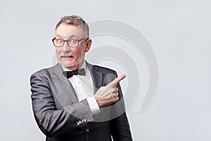 Senior business man in bow tie and suit, shirt pointing index fingers aside