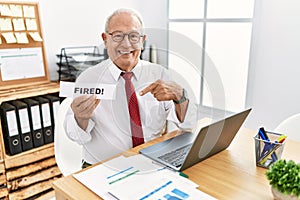 Senior business man holding fired banner at the office pointing finger to one self smiling happy and proud