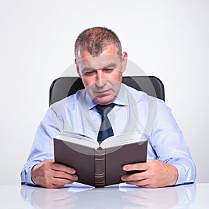 Senior business man reads at his desk