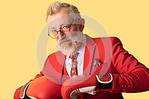 Senior business man in red suit and red boxing gloves standing in defence pose