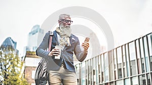 Senior business man using smartphone app walking to work - Entrepreneur drinking coffee while going to office - Job, business,