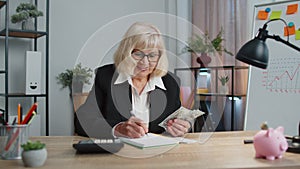 Senior business office woman accountant or banker using calculator making money cash calculations