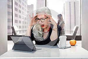 Older business woman panicked and having an anxiety attack, stressed at work office on computer for possible retirement, finances,