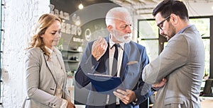 Senior businessman arguing with his younger colleague about document mistake on meeting in office