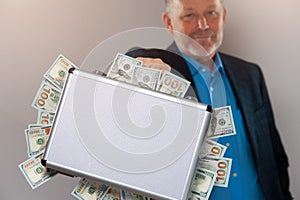 Senior businessman with briefcase full of dollars