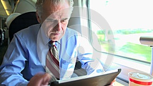 Senior Businessman Commuting On Train Using Digita