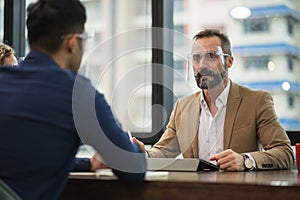 Senior businessman discussion conferencing with business team with face mask for protection virus. Meeting people in office