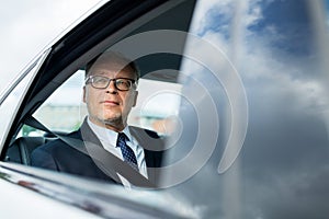 Senior businessman driving on car back seat