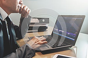 Senior Businessman in grey suit thinking and using laptop at his