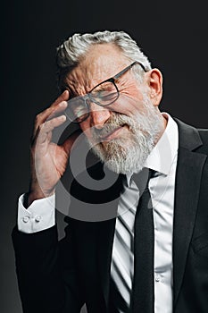 Senior businessman having headache and rubbing temples, looking with tired eyes