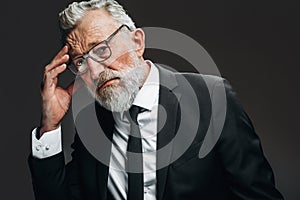 Senior businessman having headache and rubbing temples, looking with tired eyes