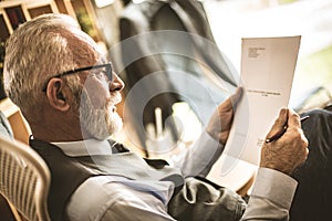 Senior businessman at his office sitting and riding documents. photo