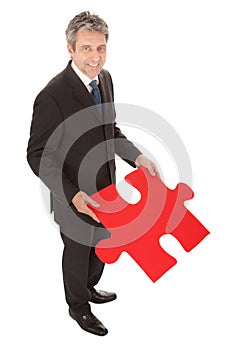 Senior businessman holding a jigsaw puzzle