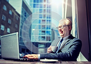 Senior businessman with laptop drinking coffee