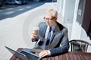 Senior businessman with laptop drinking coffee