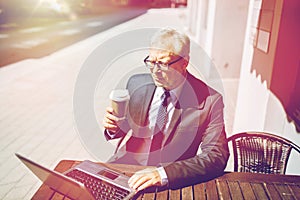 Senior businessman with laptop drinking coffee