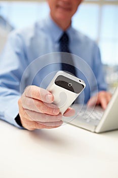 Senior businessman with laptop and phone