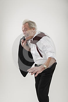 Senior businessman leaning forwards into wind photo