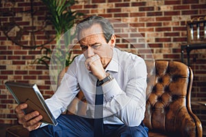 Senior businessman looking at photo with deep sadness