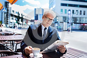 Senior businessman with newspaper drinking coffee