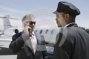 Senior Businessman Outside Private Jet On Call By Chauffeur