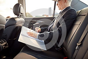 Senior businessman with papers driving in car