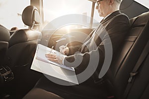Senior businessman with papers driving in car