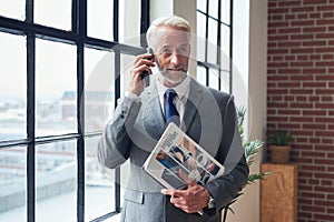 Senior businessman, phone call and office window for conversation, discussion or communication. Elderly male CEO talking