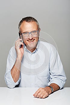 Senior businessman, phone call and studio portrait with happiness, smile and listen by gray background. Elderly man