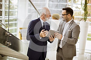 Senior businessman pointing and showing something to junior part