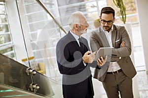 Senior businessman pointing and showing something to junior part