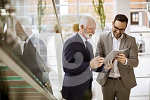 Senior businessman pointing and showing something to junior part